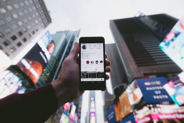 Instagram app on a smartphone with Times Square in the background
